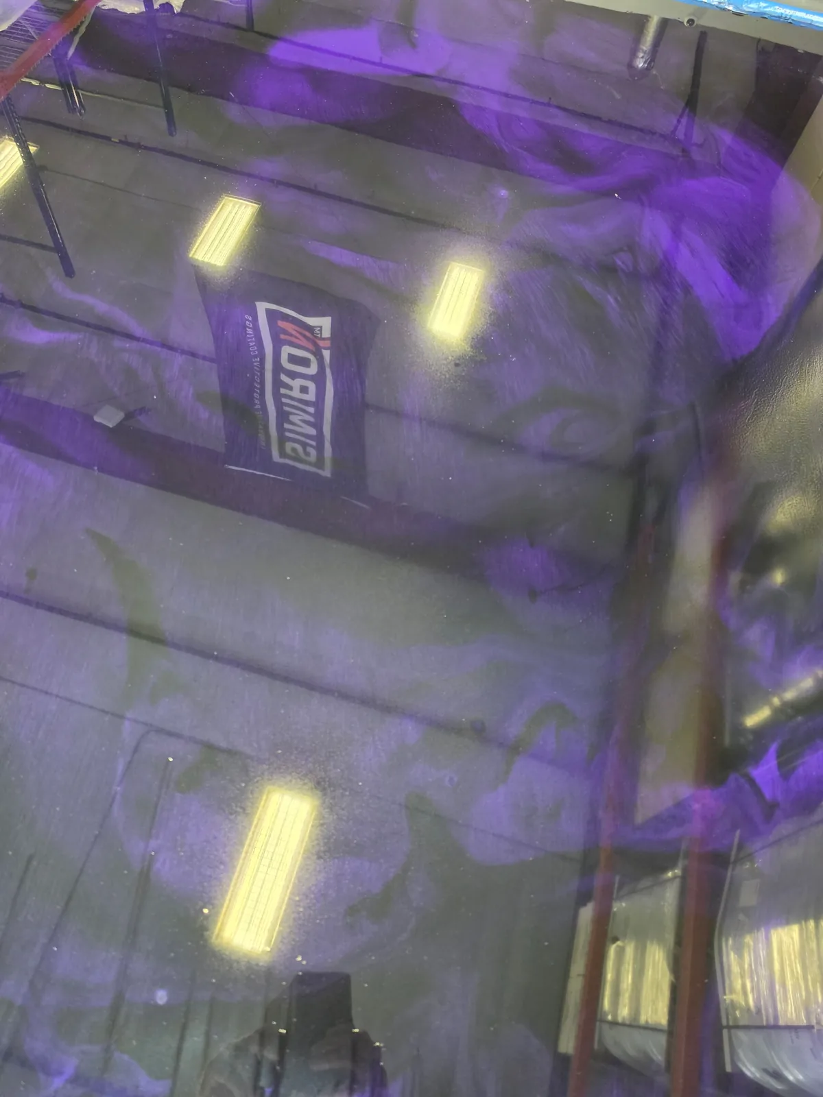 Close-up of a high-gloss metallic epoxy floor with deep purple, silver and black flowing swirls